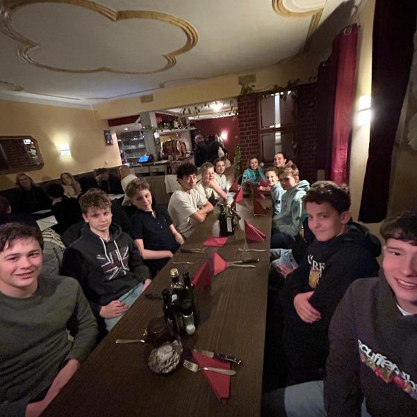 Gruppe von Jugendlichen sitzt an einem Tisch mit roten Servietten in einem gemütlichen Restaurant.