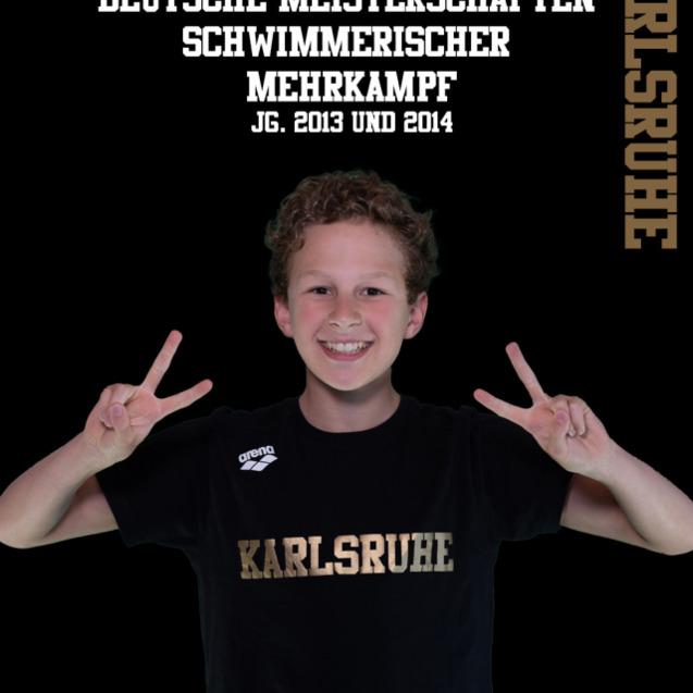 Junge mit lockigem Haar macht Peace-Zeichen, trägt schwarzes T-Shirt mit "Karlsruhe" und Hintergrund in Schwarz.