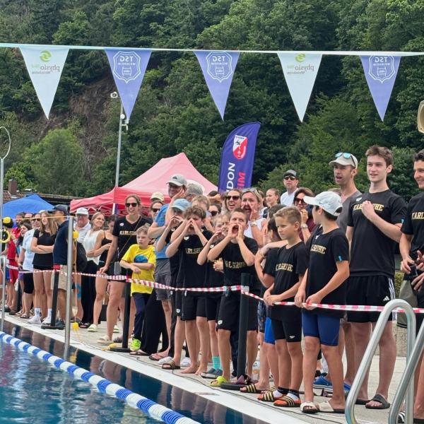 Menschenmenge am Schwimmbeckenrand, Zuschauer unterstützen Schwimmer bei einem Wettkampf in einer belebten Atmosphäre.