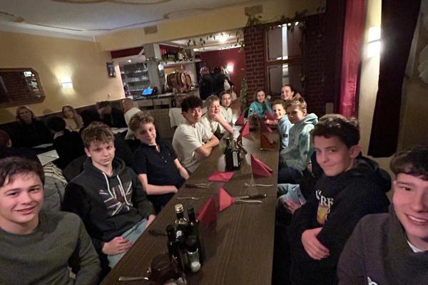 Gruppe von Jugendlichen sitzt an einem Tisch mit roten Servietten in einem gemütlichen Restaurant.