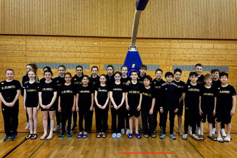 Gruppenshot von Kindern in schwarzen T-Shirts mit „Karlsruhe“, auf einem Basketballfeld in einer Sporthalle.