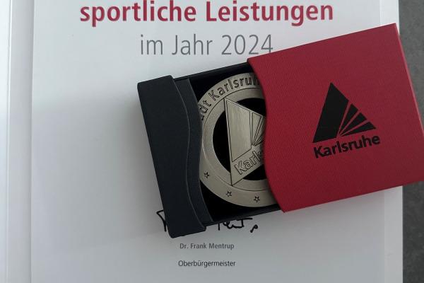 Urkunde für besondere sportliche Leistungen 2024 mit Medaille in rotem Etui, unterschrieben von Dr. Frank Mentrup.