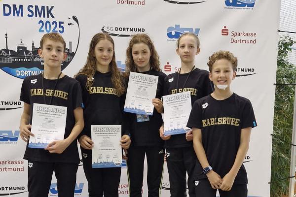 F&uuml;nf Kinder in schwarzer Sportkleidung halten Urkunden auf dem Treppchen bei einer Wettkampfveranstaltung in Dortmund.
